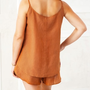 May include: A rust-colored linen tank top and matching shorts set. The tank top has thin straps and a scoop neck. The shorts have a relaxed fit.