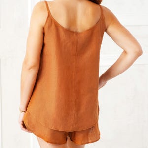 May include: A rust-colored linen tank top and matching shorts set. The top has thin straps and a scoop neck. The shorts have a ruffled hem.