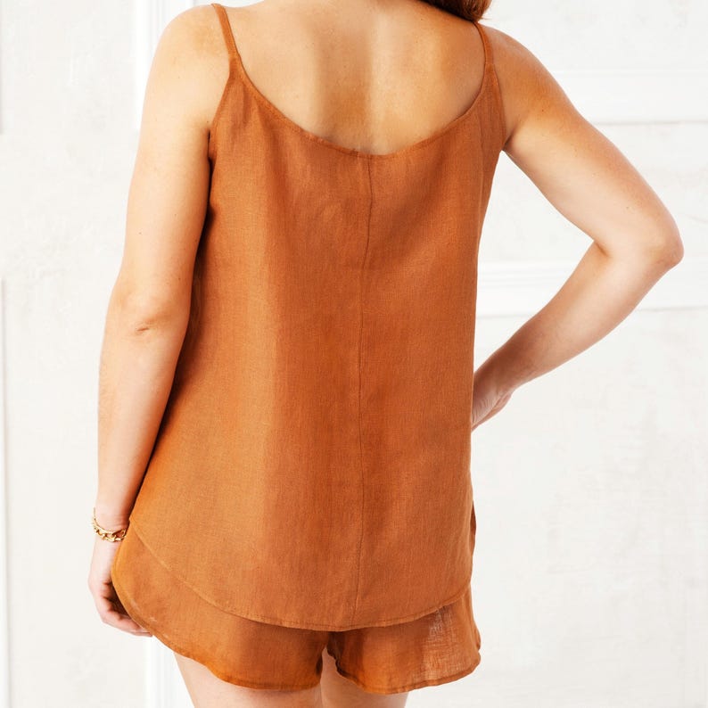 May include: A rust-colored linen tank top and matching shorts set. The top has thin straps and a scoop neck. The shorts have a ruffled hem.