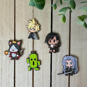 May include: Five enamel pins featuring characters from the Final Fantasy video game series. The pins are on a wooden background. The characters include Cloud, Tifa, Cactuar, and a black cat with a crown.