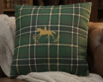 May include: Green plaid throw pillow with a gold equestrian design. The pillow features a dark green and black plaid pattern with red accents. The gold design includes a horse and rider with laurel leaves.