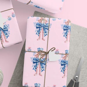 Eleganckie opakowanie na prezent w kształcie kokardy, pastelowy różowy papier do pakowania, niebieski kwiatowy wzór kokardy, urocze opakowanie na święta, luksusowy arkusz do pakowania prezentów