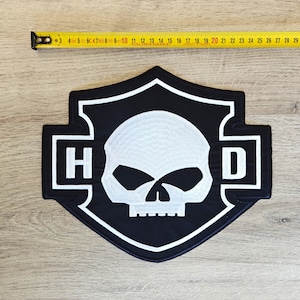 May include: Black and white embroidered patch with a skull and crossbones design. The patch features the letters "H-D" on either side of the skull.