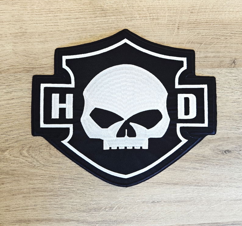May include: Black and white embroidered patch with a skull and crossbones design. The patch features the letters "HD" in white on a black background.