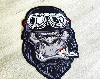 May include: Embroidered patch depicting a gorilla wearing a black helmet and white goggles. The gorilla has a stern expression, a cigar in its mouth, and the text "Hell Yeah" on the cigar. The patch is black, grey, and white.
