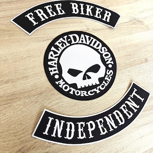 Może przedstawiać: Trzy czarno-białe naszywki motocyklowe. Górna naszywka z białym, łukowatym napisem "FREE BIKER". Środkowa naszywka to okrąg z grafiką czaszki i napisem "HARLEY-DAVIDSON MOTORCYCLES" w białym kolorze. Dolna naszywka z białym, łukowatym napisem "INDEPENDENT".
