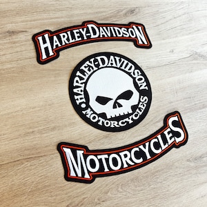 Puede incluir: Tres parches de motocicleta Harley-Davidson en blanco y negro. El parche superior es una pancarta curva con el texto "Harley-Davidson". El parche del medio es un círculo con el texto "Harley-Davidson Motorcycles" y una calavera blanca en el centro. El parche inferior es una pancarta curva con el texto "Motorcycles".
