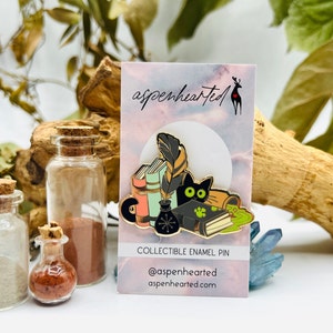 Épingle en émail chat phosphorescent | Chat noir cachant des livres de sorts de sorcière effrayants et des bouteilles de potion, cottagecore drôle