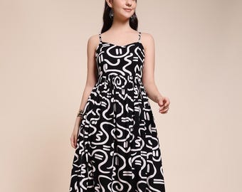 May include: A black and white midi dress with a unique abstract pattern. The dress features thin spaghetti straps and a flared skirt. The design consists of white, curved lines on a black background. The dress falls to mid-calf length.