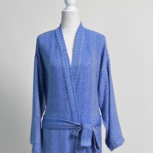May include: A blue and white chevron patterned robe with a matching belt. The long-sleeved robe is displayed on a white mannequin. The robe is made of a soft, lightweight material.
