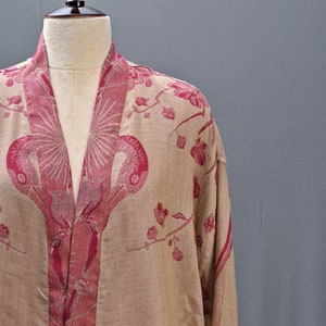 May include: A beige kimono-style robe with a floral and bird pattern in shades of red. The robe is displayed on a mannequin, showcasing the intricate design and flowing fabric. The robe's design features a repeating pattern of stylized birds and flowers.