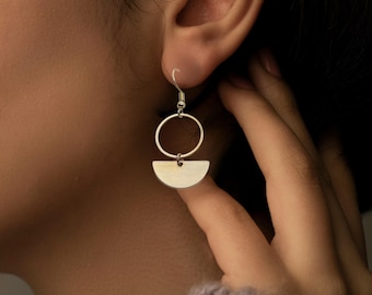 May include: Silver earrings with a half-circle and a circle design.