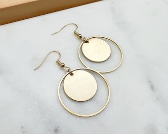 May include: A pair of gold hoop earrings with a smaller circle hanging inside each hoop.