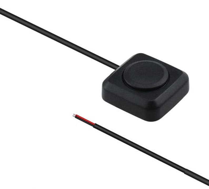 Pode incluir: Um bot&atilde;o preto de formato quadrado com um centro circular, conectado a um fio preto. O fio tem fios vermelhos e pretos expostos na extremidade. Este &eacute; provavelmente um componente eletr&ocirc;nico.