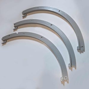 May include: Three curved, gray plastic pieces, each with a different radius, are arranged on a white surface. The pieces have a channel on one side and small holes. Numbers 1, 2, and 3 are printed on the top piece.