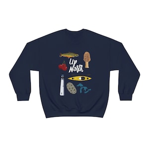 May include: Navy blue sweatshirt with a white graphic of a lighthouse, a kayak, a mushroom, a cherry, a fish, and the text "Up North" on a dark blue background.