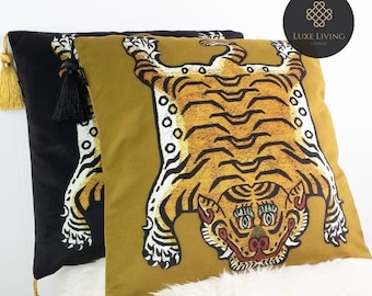 May include: Two decorative throw pillows with tassels. One pillow is black velvet with a gold tassel. The other pillow is mustard yellow with a black tassel and a tiger print.
