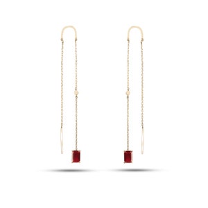 May include: A pair of gold earrings with a red gemstone dangling from each. The earrings are made of a thin chain with a small gold circle at the top.