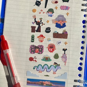 May include: A sheet of paper with colourful stickers featuring characters and scenes from the animated film Spirited Away. The stickers include a No Face character, a dragon, a bathhouse, and other characters from the film.