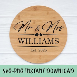 May include: A round wooden cutting board with the text "Mr. & Mrs. Williams Est. 2025" in black lettering. Two small hearts are above the last name.