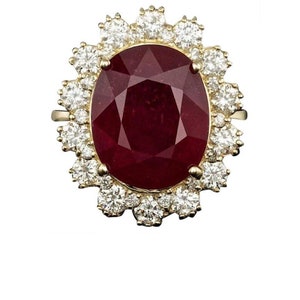 May include: A gold ring with a large oval ruby surrounded by a halo of smaller diamonds.
