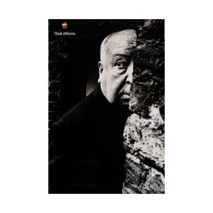 May include: A black and white poster featuring a portrait of Alfred Hitchcock peering from behind a textured stone wall. The iconic Apple logo in rainbow colors appears in the top left corner above the white text that reads Think different.