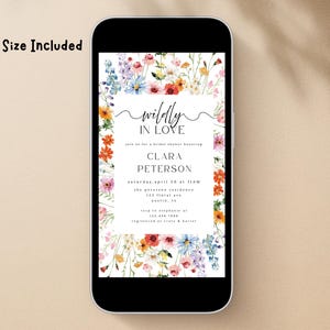 May include: A digital invitation displayed on a smartphone screen featuring a watercolor floral border with red, orange, blue, and pink wildflowers. The text reads "wildly IN LOVE", "join us for a bridal shower honoring CLARA PETERSON", and event details.