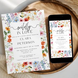 May include: A rectangular bridal shower invitation and a smartphone displaying the same design, both featuring a colorful watercolor wildflower border and black text that reads "wildly IN LOVE" followed by event details for Clara Peterson.