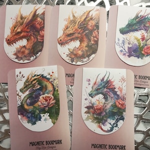 以下が含まれることがあります： 水彩画のドラゴンのイラストが描かれた、5つのマグネットブックマークのセットです。 ドラゴンは赤、オレンジ、緑、青の色合いで、花の要素に囲まれています。 各ブックマークはピンク色の裏地で、「MAGNETIC BOOKMARK」の文字が印刷されています。