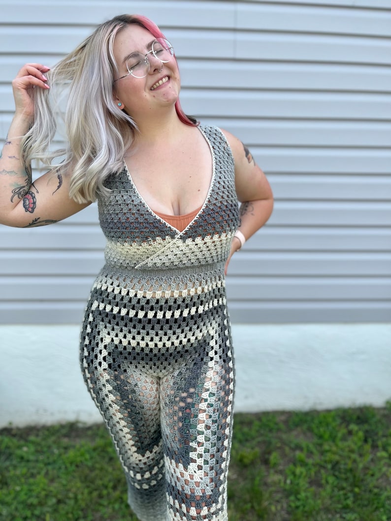 May include: A woman wearing a gray and white crochet maxi dress with a deep V-neckline. The dress has a geometric pattern and is sleeveless.