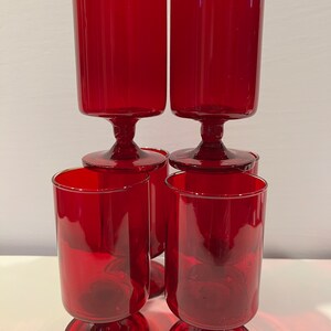 May include: Set of six red glass goblets with a stemmed base. The goblets are clear and have a smooth, polished finish.