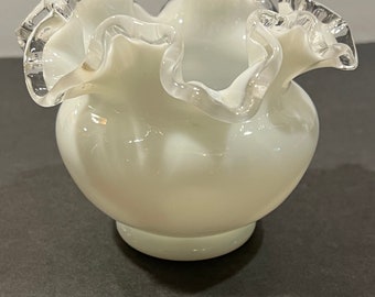 May include: A white glass vase with a ruffled, scalloped rim. The rim has a silver trim.