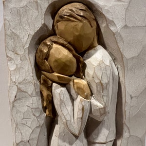 May include: A white ceramic wall sculpture of a couple embracing. The sculpture is in a rustic style with a textured surface.