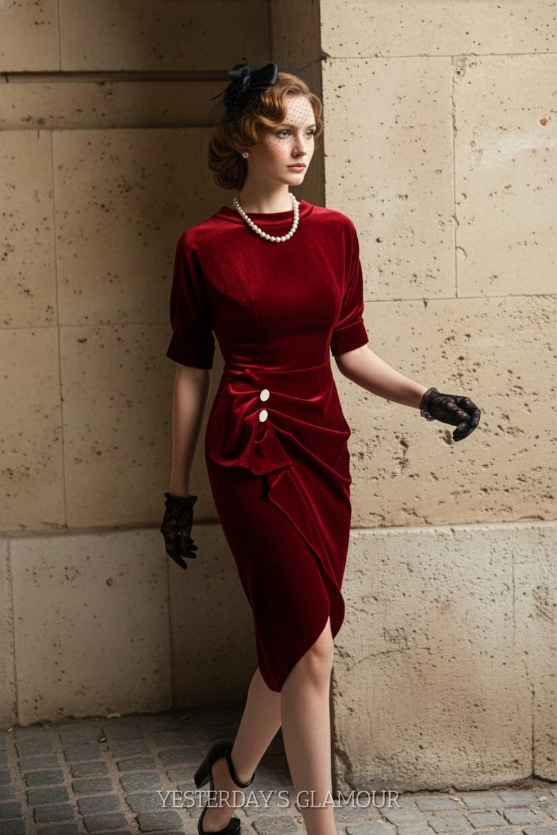 May include: A vintage-style, knee-length, red velvet dress with short sleeves and a draped design. The dress has two white buttons and is worn with black gloves and heels. A pearl necklace and a black headpiece complete the look. The text "YESTERDAY'S GLAMOUR" is visible.