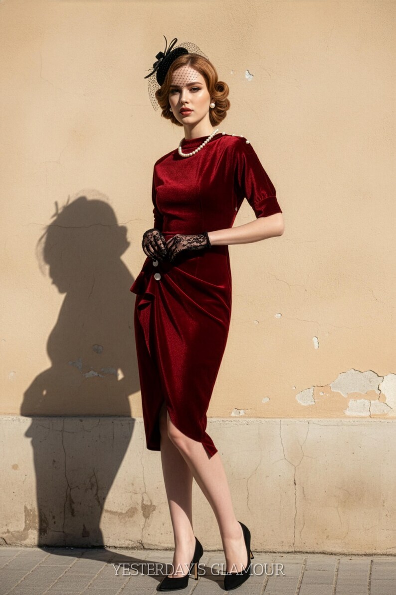May include: A burgundy velvet dress with a draped front and button detail. The model wears a black hat with a veil, black lace gloves, and black heels. The text "YESTERDAYS GLAMOUR" is visible at the bottom of the image.