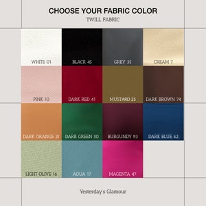Puede incluir: Una carta de colores que muestra 12 colores de tela diferentes con sus nombres y n&uacute;meros. Los colores incluyen blanco, negro, gris, crema, rosa, rojo oscuro, mostaza, marr&oacute;n oscuro, naranja oscuro, verde oscuro, burdeos, azul oscuro, verde oliva claro, aguamarina y magenta.