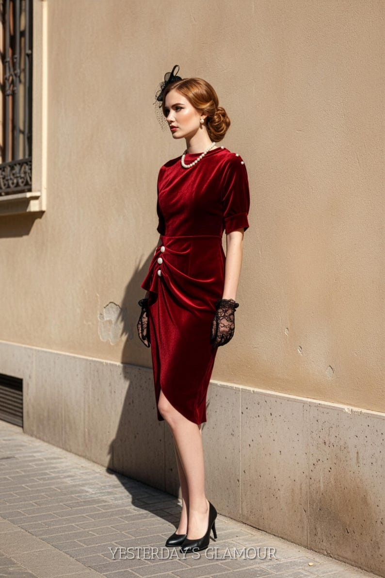 May include: A burgundy velvet dress with a draped design and button details. The dress features short sleeves and a knee-length hemline. The model is wearing black heels and lace gloves. The text "YESTERDAY'S GLAMOUR" is visible at the bottom.