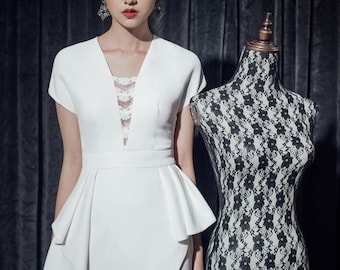 May include: A woman in a white dress with a V-neck and lace detail stands next to a black and white patterned dress form. The dress has a peplum and a thigh-high split. The text "YESTERDAY'S GLAMOUR" is at the bottom.