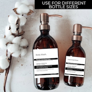 May include: Two amber glass bottles with copper pumps, one labeled "Body Wash. Natural Liquid Body Soap" and the other labeled "Hand Sanitizer. Natural Hand Sanitizer". Both bottles have white labels with black text.