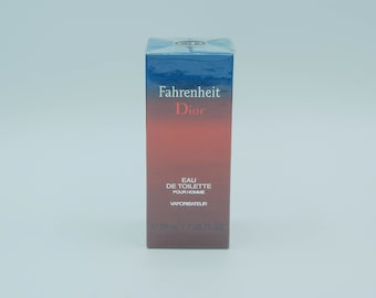 Puede incluir: Caja rectangular de Fahrenheit Dior Eau de Toilette para hombre. La caja tiene un diseño degradado, que transiciona de una parte superior azul oscuro a una base roja. El nombre del producto y la marca están impresos en blanco y rojo.