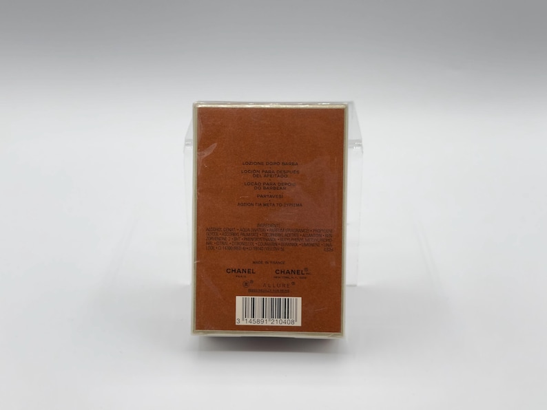 May include: A rectangular brown box with text in multiple languages, including "LONDON PARIS NEW YORK" and "PARFUM". The box is wrapped in clear plastic. The brand name "CHANEL" is visible on the bottom of the box.