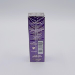 May include: A rectangular, purple perfume box with text in white. The box is sealed in clear plastic. The text includes "EAU DE TOILETTE" and other product information. A barcode is visible on the side.