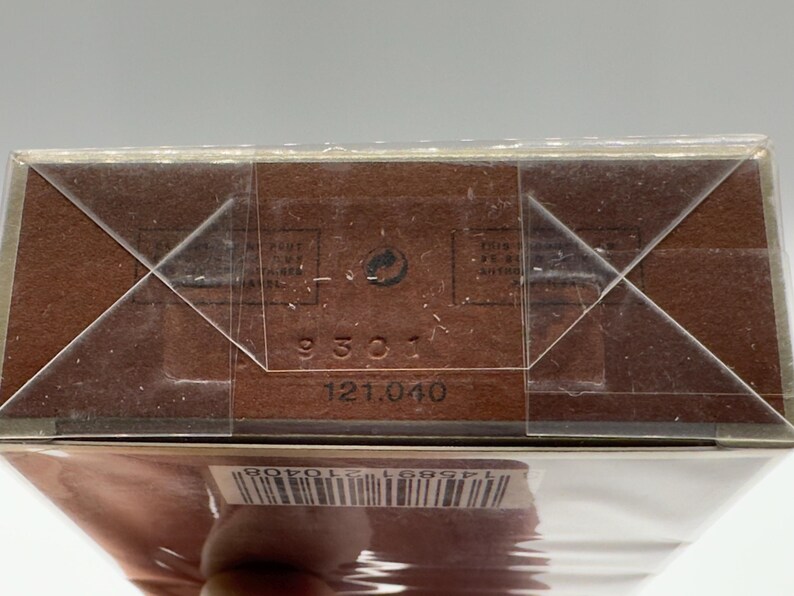 May include: Close-up of a brown cardboard box with a clear plastic wrap. The box has a barcode and the numbers "9301" and "121.040" printed on it. The box is sealed with clear tape.