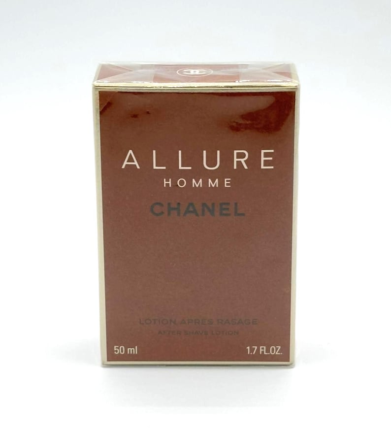May include: A brown box of Chanel Allure Homme after shave lotion. The box has gold trim and the Chanel logo on top. The front of the box has the words "ALLURE HOMME CHANEL" in white and brown lettering. It contains 1.7 fl. oz. (50 ml).