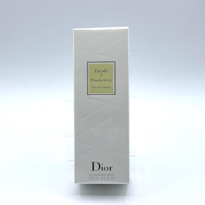 May include: A white rectangular box of Dior "Escale à Pondichéry" Eau de Toilette. The box has a geometric pattern and a green label with the product name. The bottom of the box has the Dior logo and the volume, 4.2 fl oz.