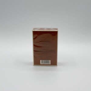 May include: A rectangular brown box with a barcode on the bottom. The box is wrapped in clear plastic and has a light brown border. The background is a plain white surface.
