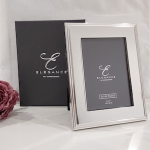 May include: Silver-plated picture frame with a bevelled edge and a black mount. The frame is 5 x 7 inches (13 x 18 cm) and has the text "Elegance by Impressions" on the front.
