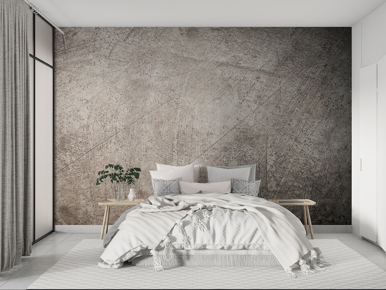May include: A white bed with a white blanket and pillows in a bedroom with a textured grey wall and a white rug.