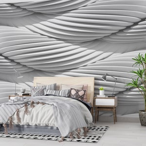 May include: A white bedroom with a bed, a nightstand, a plant, and a white wall with a 3D wave pattern.