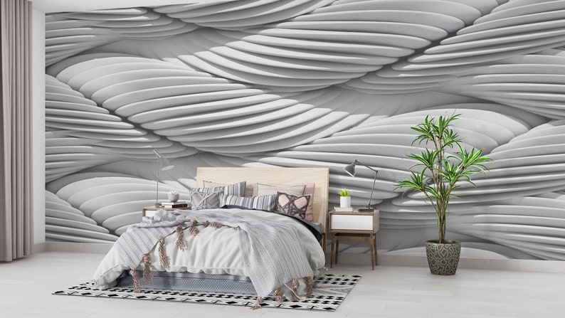 May include: A white bedroom with a bed, a nightstand, a plant, and a white wall with a 3D wave pattern.